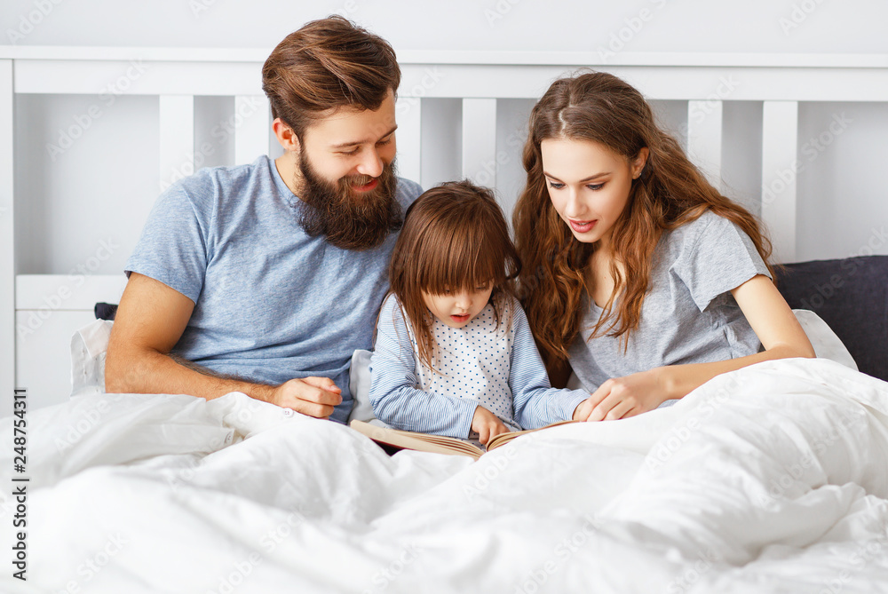 happy family mother, father and child read a book, a fairy tale in bed happy family mother, father and child read a book, a fairy tale in bed