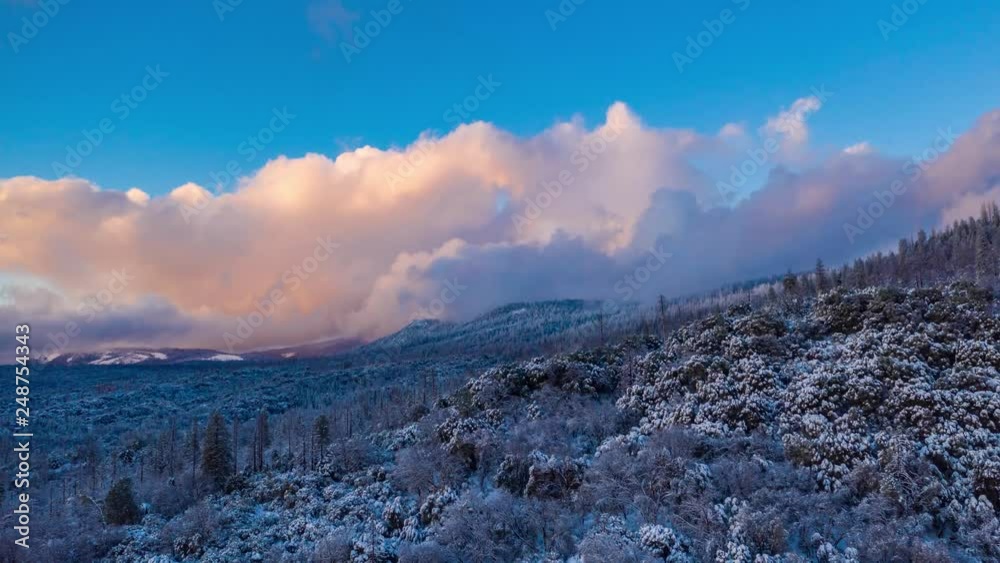 Aerial time lapse flying forward over a snow covered landscape in winter. Dramatic beautiful clouds moving fast in hyper lapse.