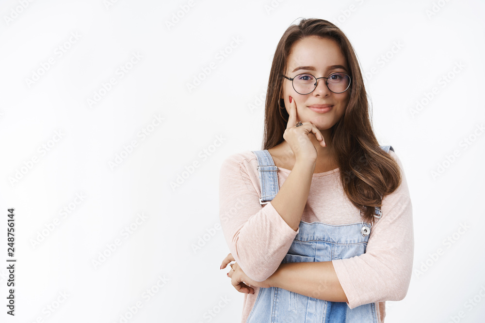 Waist-up shot of skillful and creative attractive caucasian 20s woman in glasses having interesting idea or plan in mind smiling and touching cheek with finger as wanting implement dream in reality Waist-up shot of skillful and creative attractive caucasian 20s woman in glasses having interesting idea or plan in mind smiling and touching cheek with finger as wanting implement dream in reality