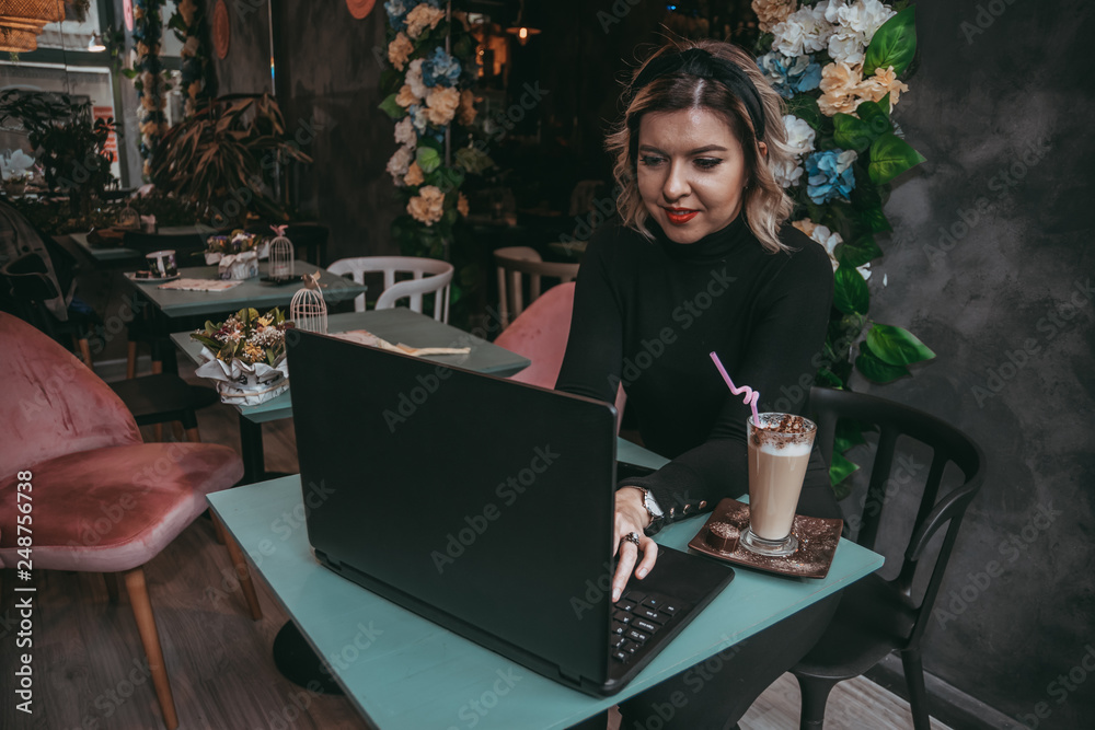 Girl typing on laptop and drinking coffee