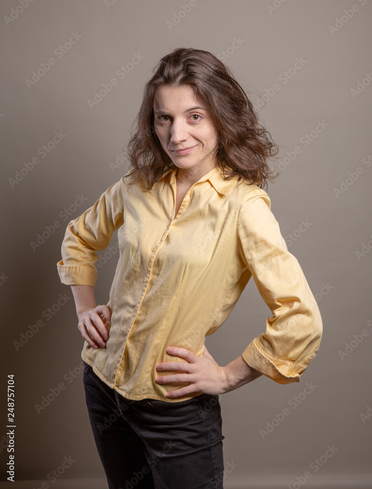 Woman in yellow shirt in studio on grey background Woman in yellow shirt in studio on grey background