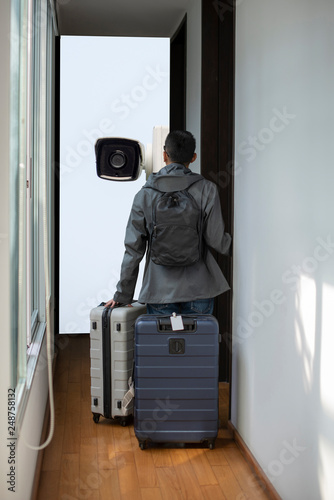 A traveler is looking at the CCTV surveillance system and thinking about his privacy while staying this modern small hotel. He is about to check in with suitcases and backpacks in the morning.