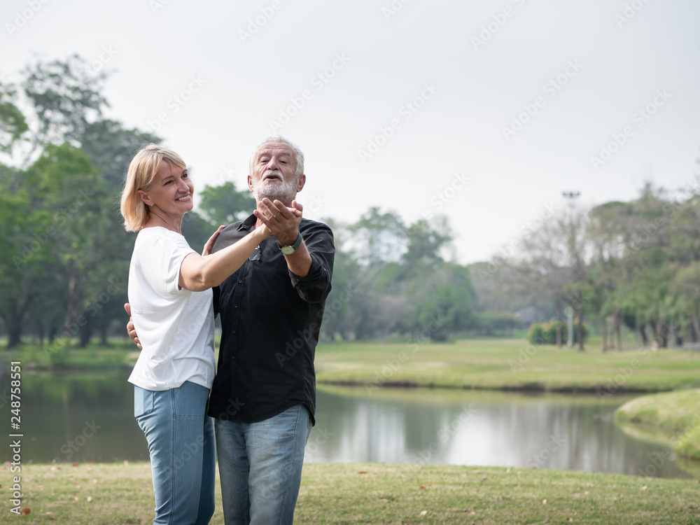 A happy senior couple smiling dancing in a park on a sunny day. relax in the forest spring summer time. free time, lifestyle retirement grandparents concept