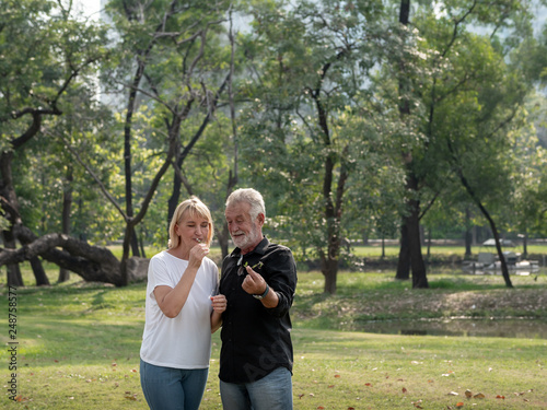 Happy senior man and woman couple in a park on a sunny day. relax in the forest spring summer time. free time, lifestyle retirement grandparents concept. © xreflex