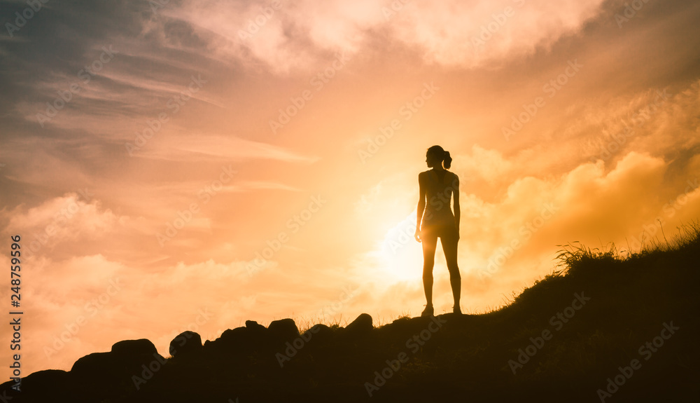 Thoughtful woman standing on mountain alone watching the beautiful sunset. People, adventure, active lifestyle concept. 