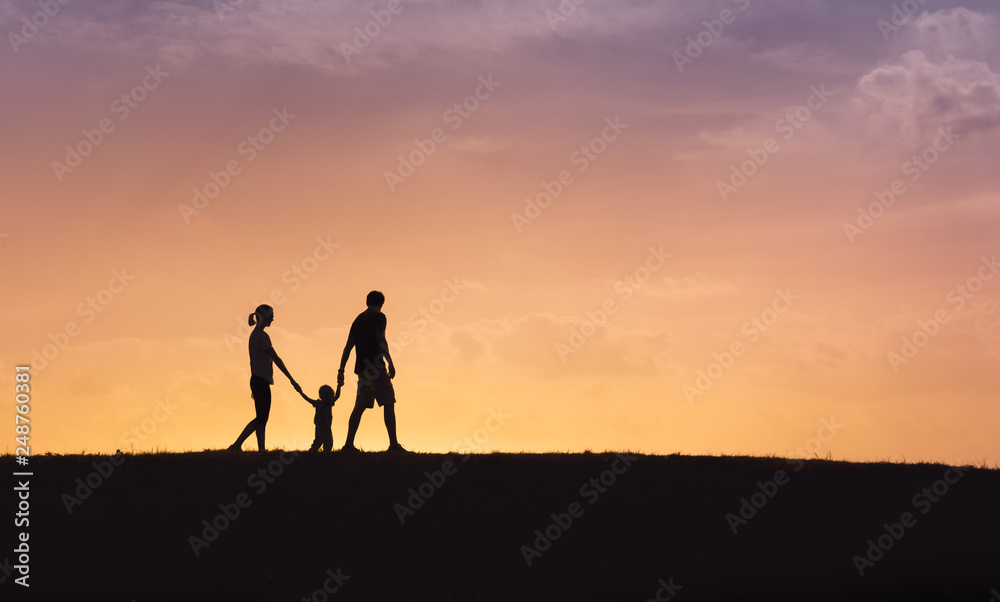 Mother father and little boy holding hands walking in the park