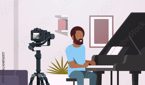 guy musical blogger recording video on camera african american man playing classical piano music blog concept modern apartment interior closeup portrait horizontal