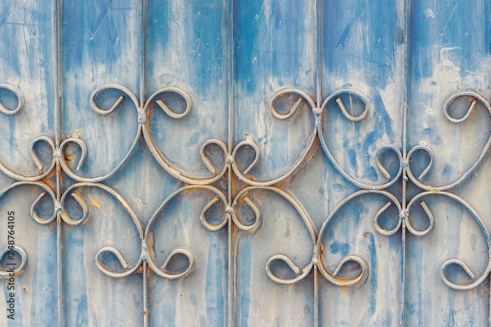 Old wrought iron bars on the gate with grunge and rusty steel background. Iron Grill Ornamental Flourish Detail Background. The old rusty fence with metallic gate pattern, curved steel background. Old wrought iron bars on the gate with grunge and rusty steel background. Iron Grill Ornamental Flourish Detail Background. The old rusty fence with metallic gate pattern, curved steel background.