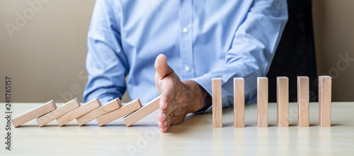 Fotografie Businessman hand Stopping Falling wooden Blocks or Dominoes