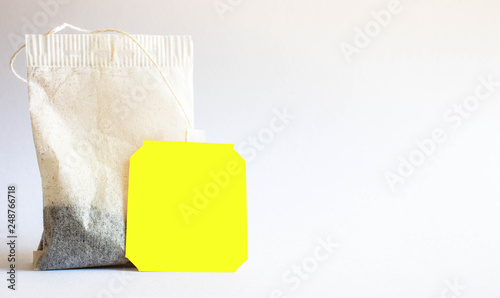 Yellow label tea bag placed on white-grey background shot in studio.
