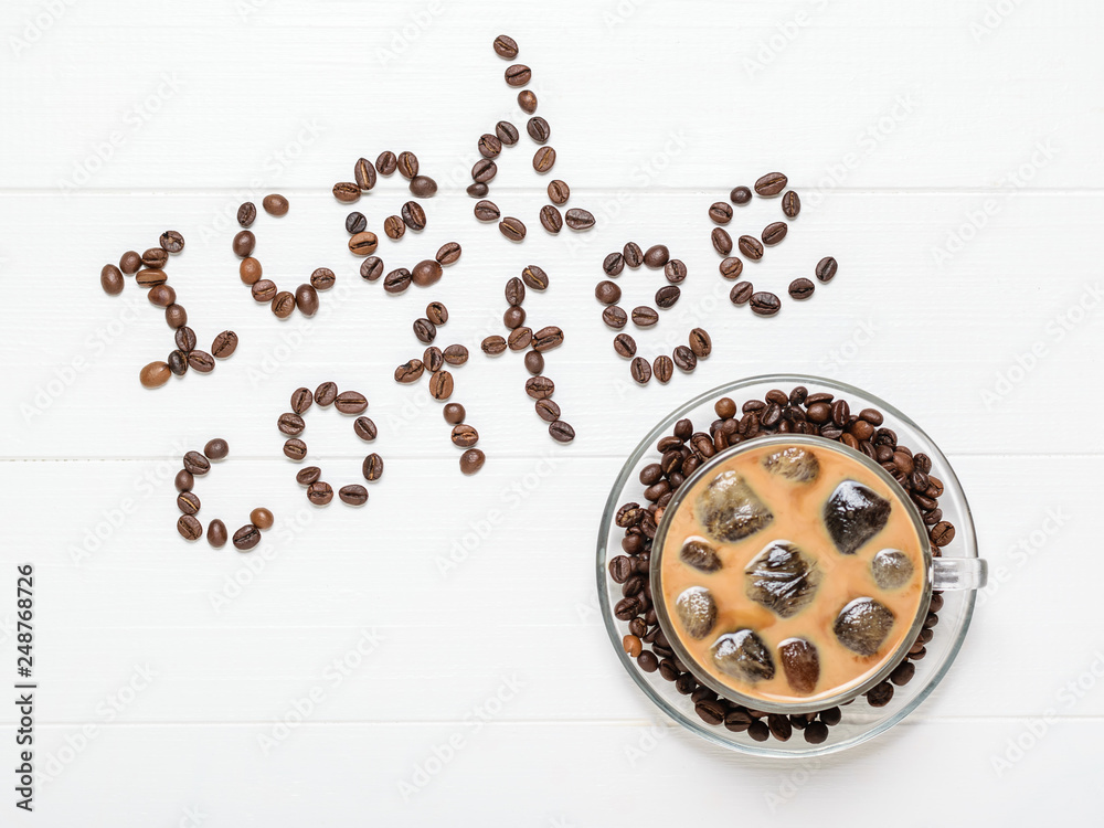 A Cup of coffee with floating icicles and an inscription of ice coffee on a white table. The view from the top.