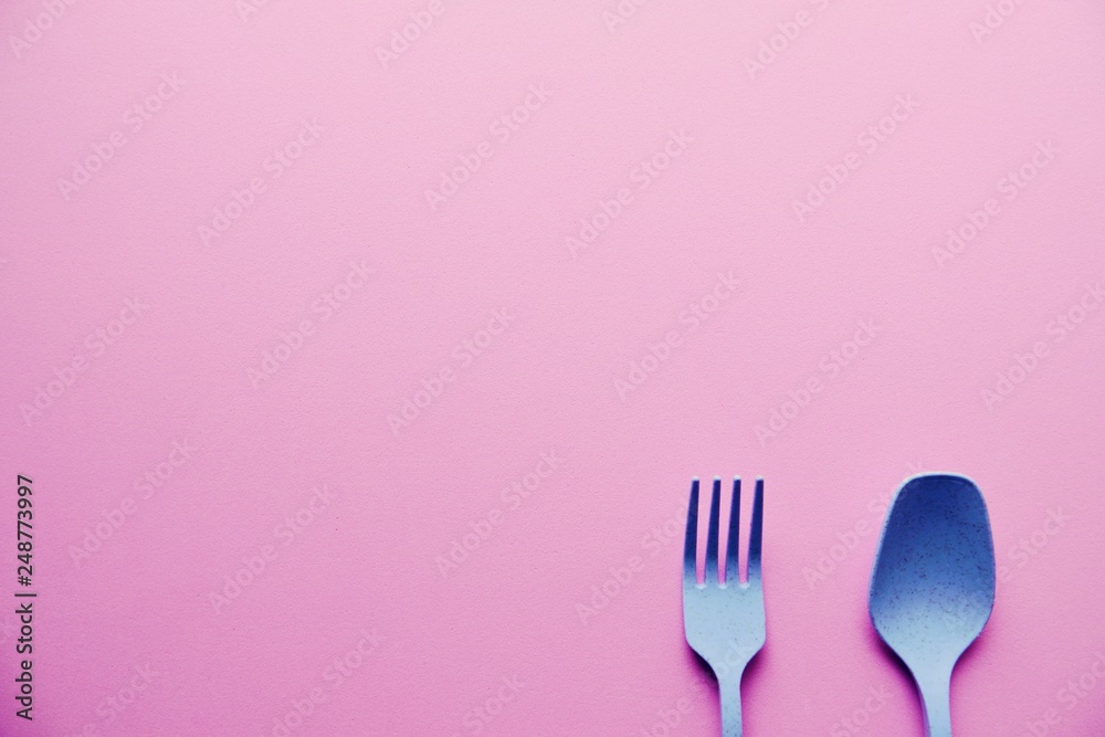 Plastic Blue Spoon and Fork On Pink Background Plastic Blue Spoon and Fork On Pink Background
