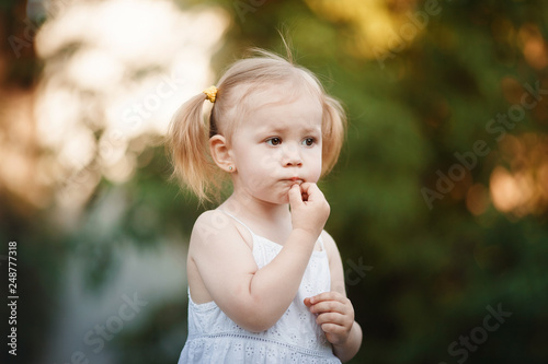 Happy little girl playing in sunny park. Baby girl playing outdoor. Portrait of little girl outdoors in summer 
