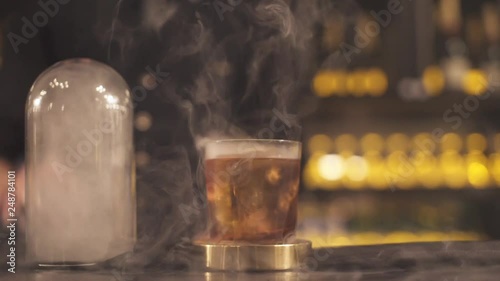 Bartender is finishing a smoky cocktail. Camera is moving forward on a slider. photo