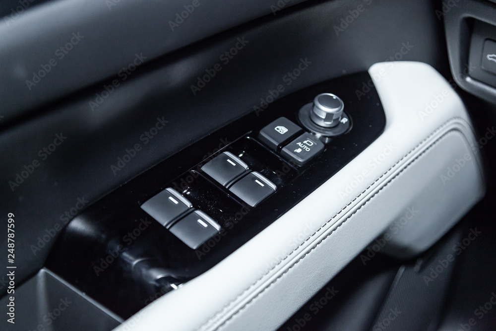 Сlose-up of the car  black interior:  the side door buttons: window adjustment buttons, door lock and other buttons.