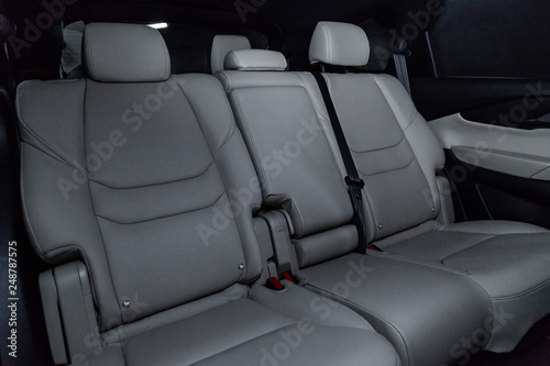 Сlose-up of the car interior: white leather rear seats and seat belts .