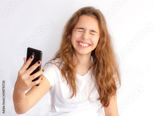 Pretty teenager girl with long hair makes selfie with funny laughing face © Anna