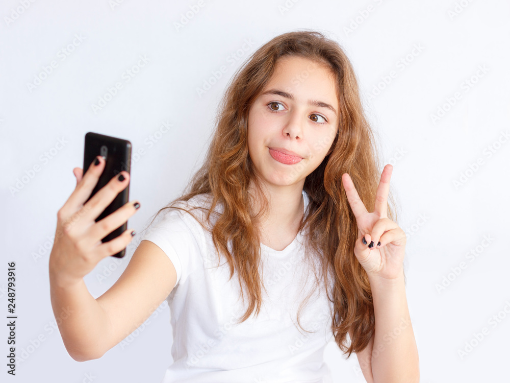 Pretty teenager girl with long hair makes selfie with funny laughing face Pretty teenager girl with long hair makes selfie with funny laughing face