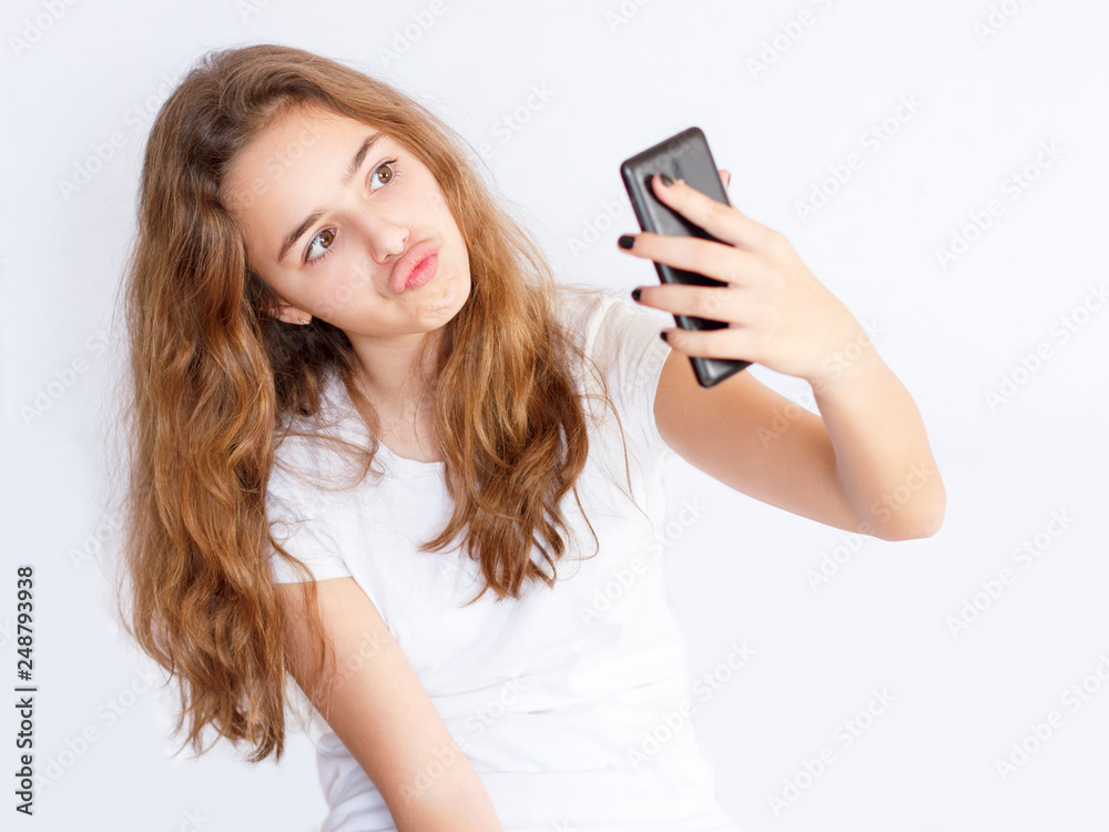 Pretty teenager girl with long hair makes selfie with funny laughing face Pretty teenager girl with long hair makes selfie with funny laughing face