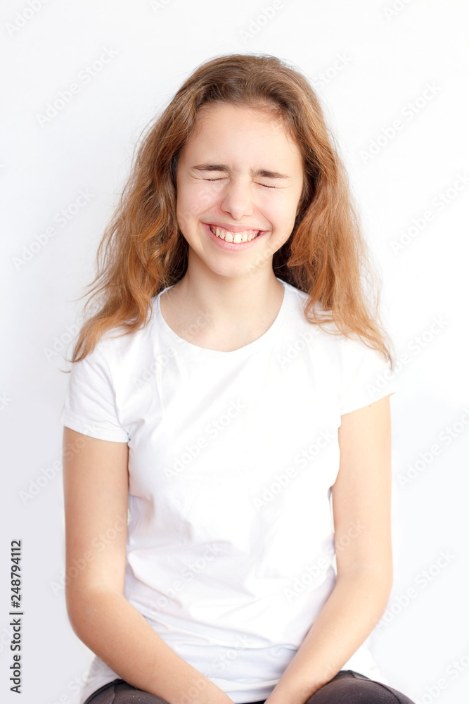 Pretty teenager girl with long hair makes very funny face and laughing with closed eyes Pretty teenager girl with long hair makes very funny face and laughing with closed eyes