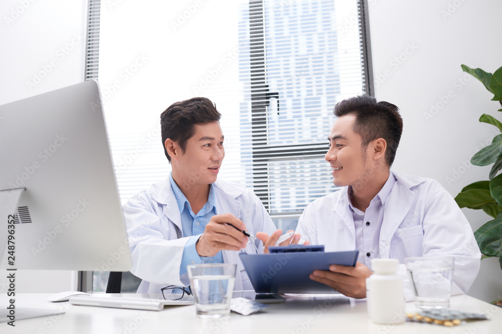 Obraz premium Two doctors holding and talking about patient on office