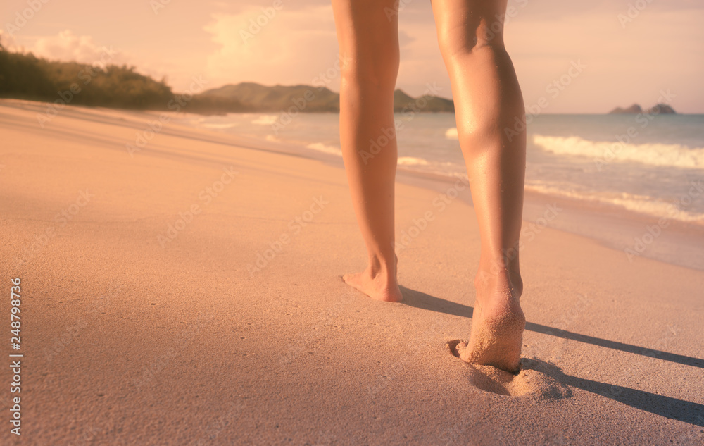 Naklejka premium Young woman walking down a beautiful white sand beach.