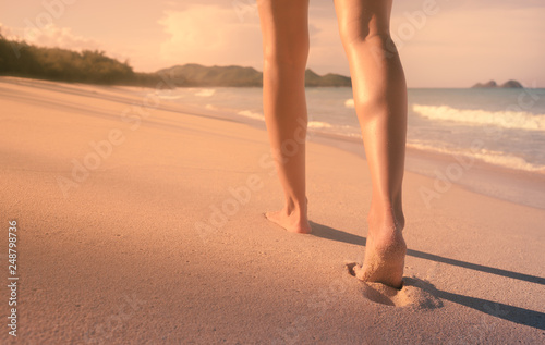 Young woman walking down a beautiful white sand beach. 