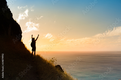 silhouette of man on top of mountain with arms up in the air. 