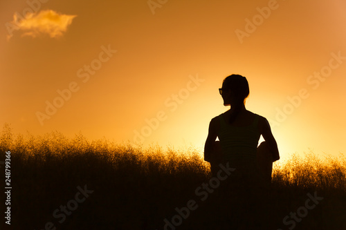 silhouette of man in grass field at sunset