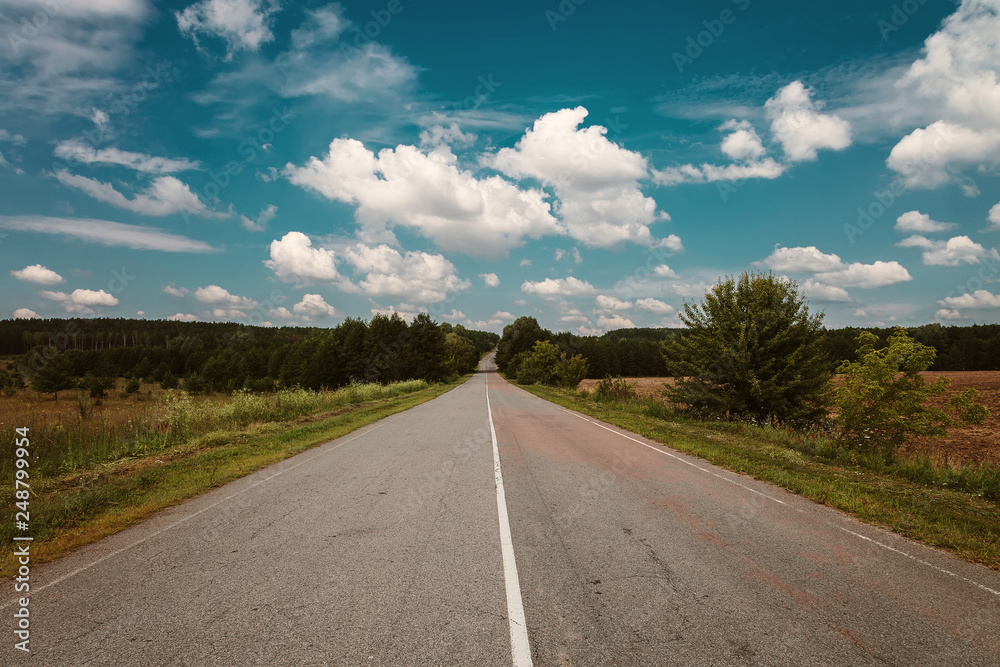 Asphalt road on a background of blue sky with clouds
