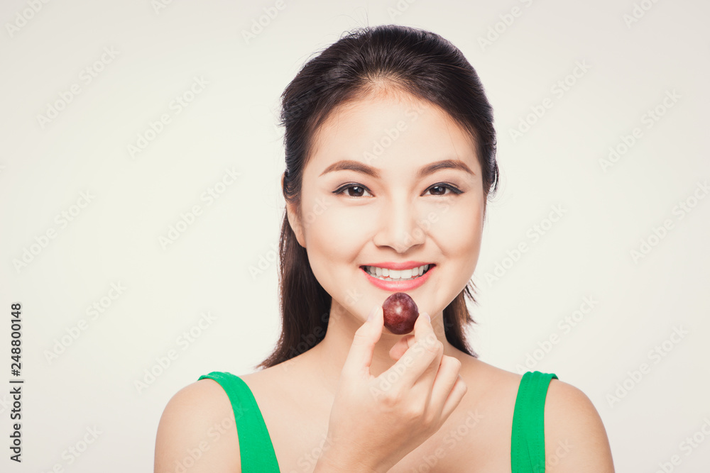 Young beautiful asian woman eating fresh grapes isolated on white background Young beautiful asian woman eating fresh grapes isolated on white background