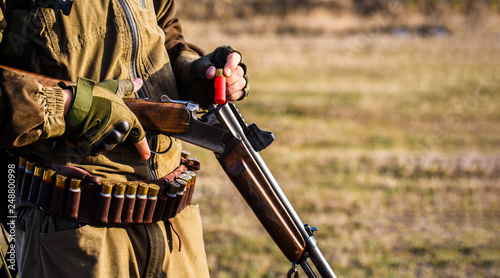 The man is on the hunt, sport. Hunter man. Hunting period. Male with a gun, rifle. Man is charging a hunting rifle. Process of hunting during hunting season. Male hunter in ready to hunt. Closeup.