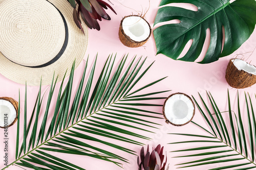 Summer composition. Tropical palm leaves, hat, coconut on pastel pink background. Summer concept. Flat lay, top view