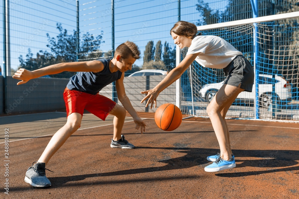 Streetball basketball game with two players, teenagers girl and boy with ball, outdoor city basketball court.