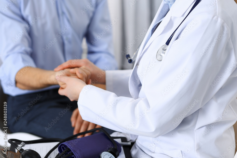 Female doctor checking blood pressure or pulse of the male patient, in hospital. Medicine and healthcare concept Female doctor checking blood pressure or pulse of the male patient, in hospital. Medicine and healthcare concept