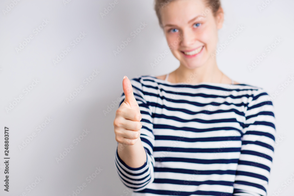Thumbs up the young girl in focus in the foreground on a white background Thumbs up the young girl in focus in the foreground on a white background
