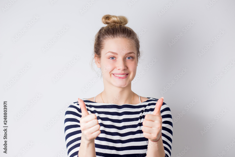 Happy and successful young business woman shows thumbs up with two hands and smiles on white background Happy and successful young business woman shows thumbs up with two hands and smiles on white background