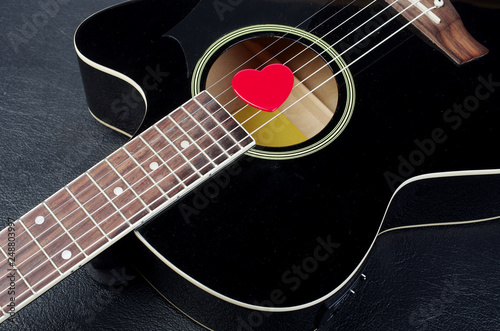 Acoustic guitar and red heart-shaped plectrum.