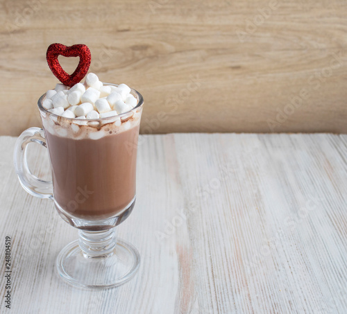 hot chocolate with red heart decor and marshmallow on wooden surface