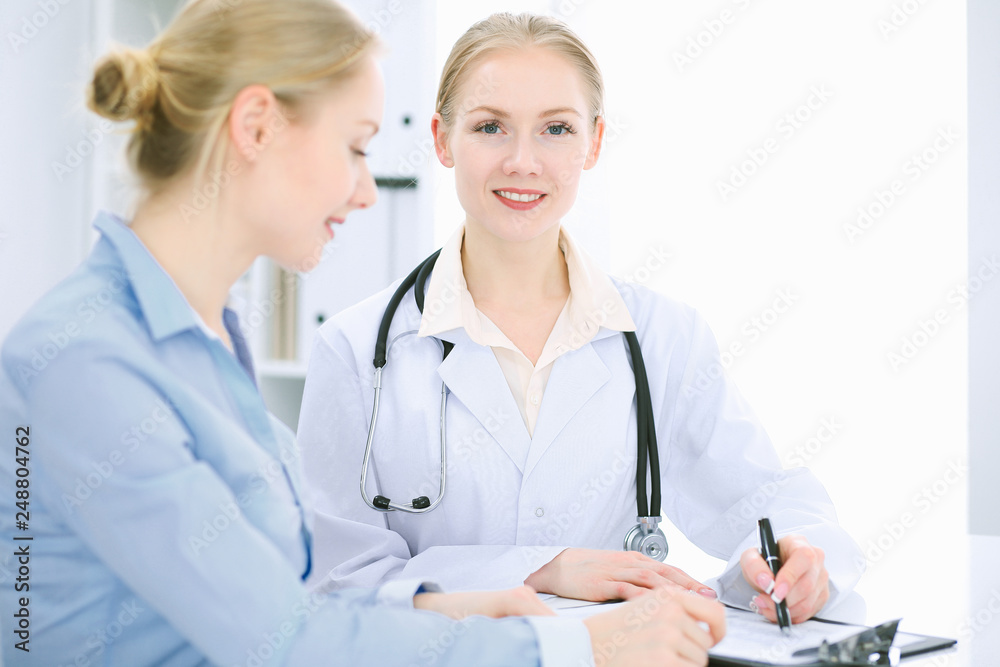 Doctor and patient talking in hospital office while sitting at the desk. Health care and client service in medicine Doctor and patient talking in hospital office while sitting at the desk. Health care and client service in medicine