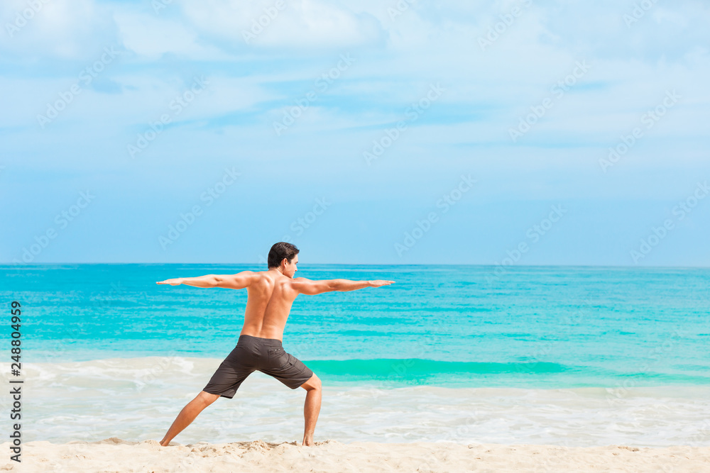 young man doing yoga on the beach