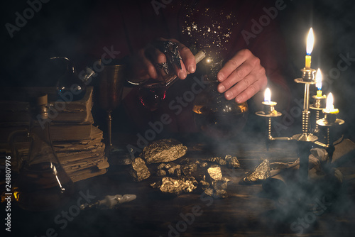 Alchemist is working at his magic table and producing a gold ore from a stones.