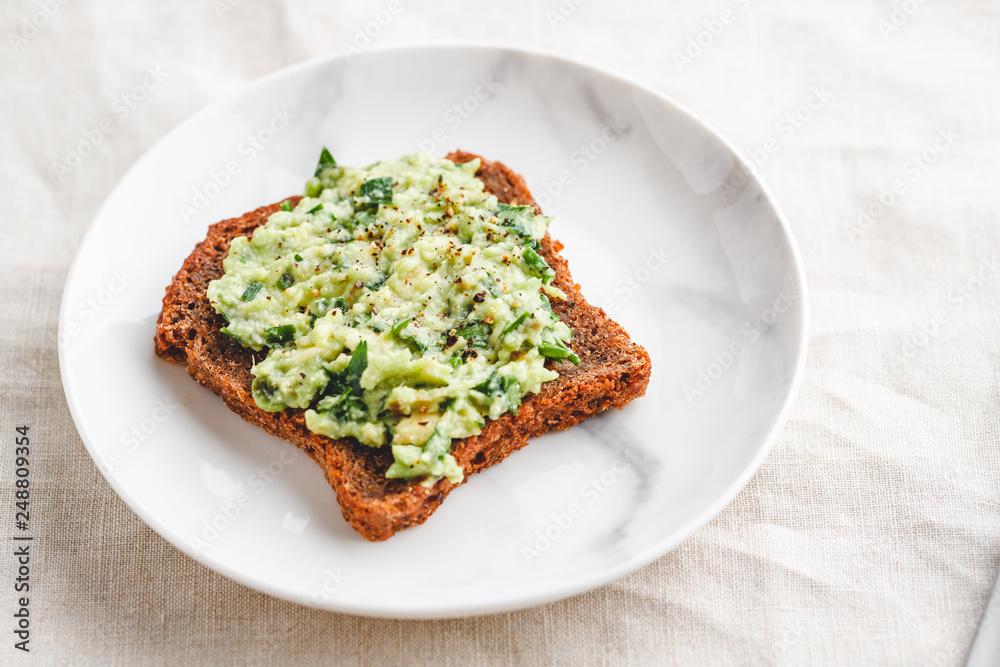 Avocado sandwich with rye bread on a plate. The concept of healthy balanced food. Avocado sandwich with rye bread on a plate. The concept of healthy balanced food.