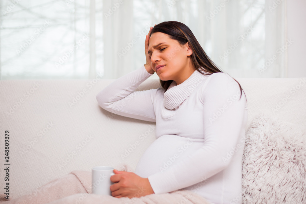 Pregnant woman is having headache, she is drinking tea. Pregnant woman is having headache, she is drinking tea.