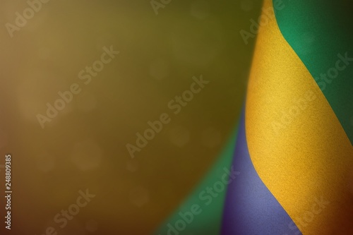 Gabon flag for honour of veterans day or memorial day. Glory to the Gabon heroes of war concept on yellow dark velvet background.