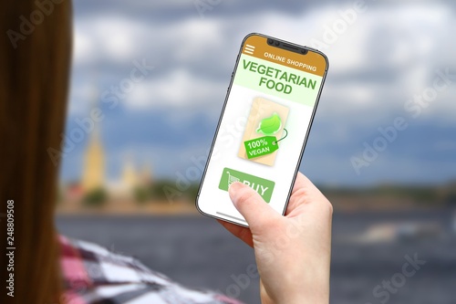 Vegetarian food idea, girl with frameless phone on blurred clouds background