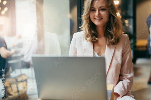 Happy manager having an online video call from abroad using modern laptop computer and free wifi in a cafe discussing plans and news with her colleagues and laughing