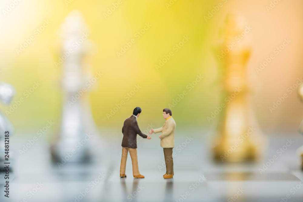 Business decision making concept. Miniature people : small businessman figure standing and walking on chessboard with chess pieces Business decision making concept. Miniature people : small businessman figure standing and walking on chessboard with chess pieces