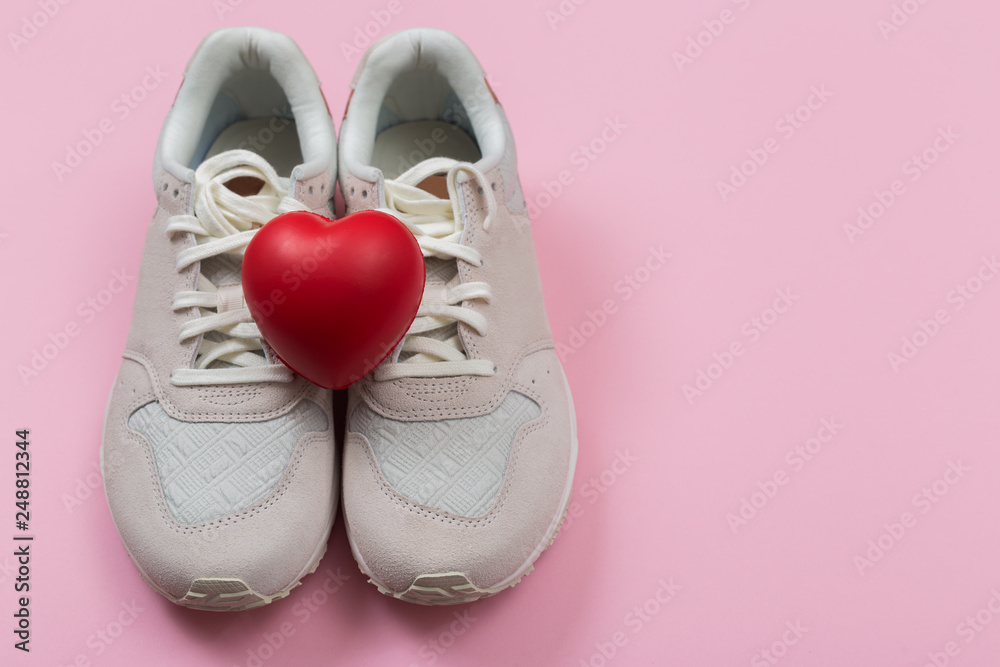 women's sneakers on the red background with heart symbol for the Valentine's Day or Shoe Sale