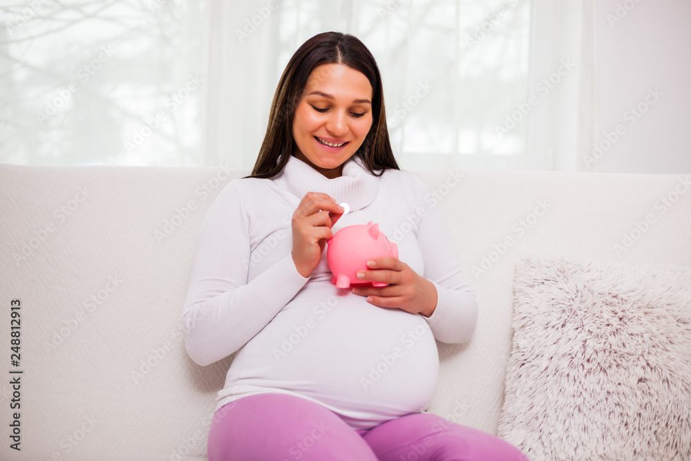 Happy pregnant woman saving money for her child. Happy pregnant woman saving money for her child.
